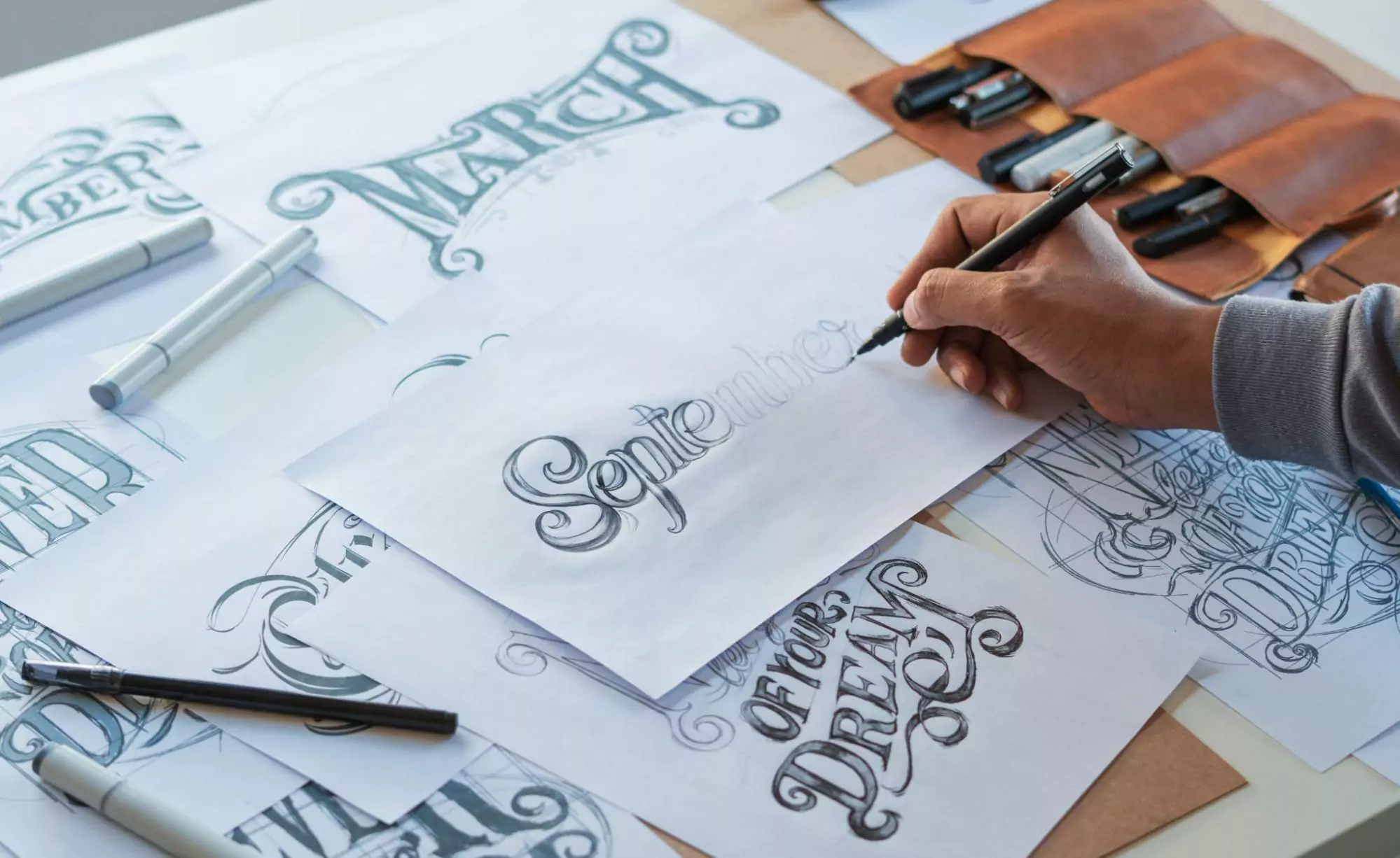 Font designer creating calligraphic designs with a pen and paper