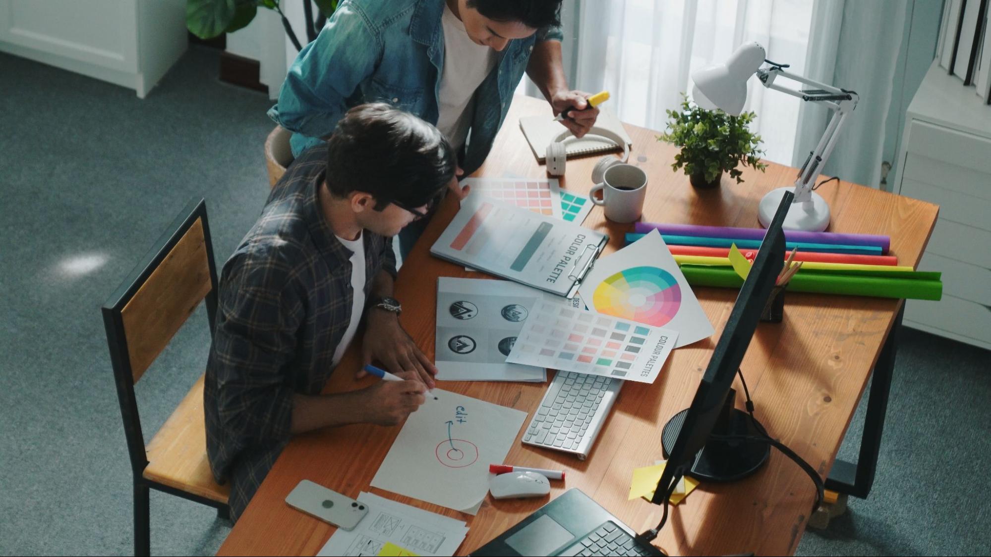 Graphic designers using the color wheel to design a logo.
Graphic designers using the color wheel to design a logo.