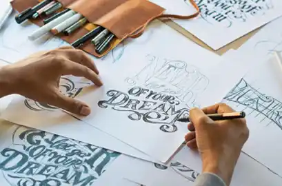 Calligraphy artist using pen on paper, creating elegant lettering.