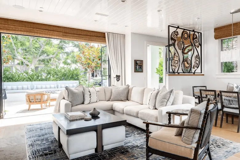 Living room with large windows and doors opening to a balcony with plants.
Living room with large windows and doors opening to a balcony with plants.