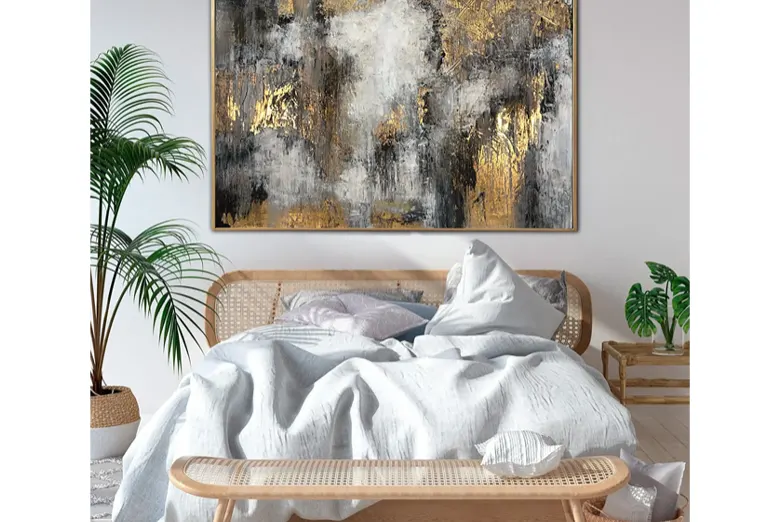 A bedroom with a bed and big painting.
