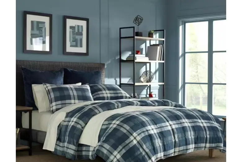 A bed with blue paid blanket and pillows.
