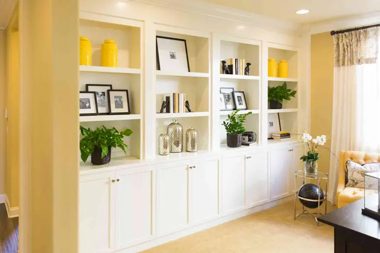 A well-lit living room with wooden shelves that have plants, frames and showpieces on it
A well-lit living room with wooden shelves that have plants, frames and showpieces on it