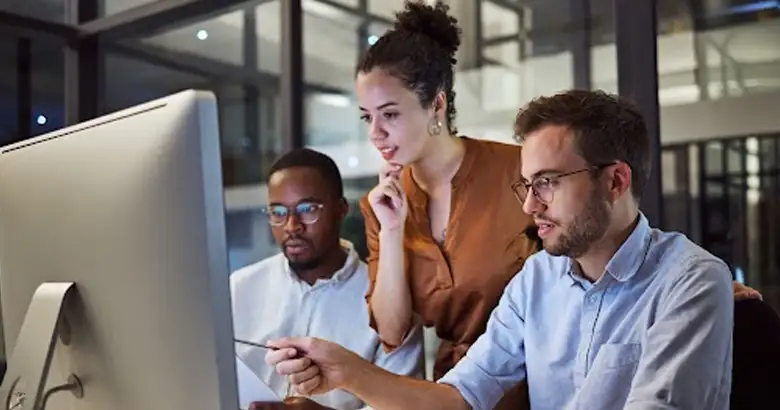 Three young professionals discussing Design Thinking benefits on a computer screen, focusing on how to enhance their products and services.