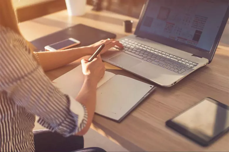 A graphic design student making notes while attending Adobe Illustrator classes.