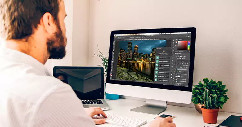 Middle-aged professional using Photoshop software on a computer.