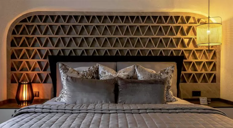 A bedroom with sculptural headboard