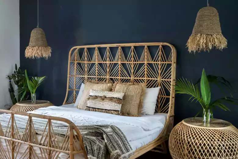 Bedroom with a rattan bed frame, and plants, highlighting modern furniture design.
