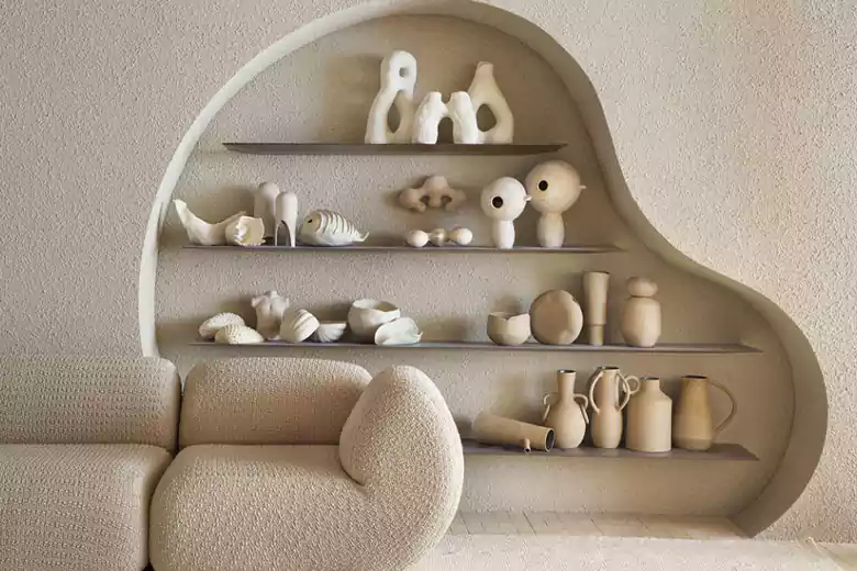A curved, built-in shelf displays minimalist white ceramic art pieces in this example of modern furniture design.