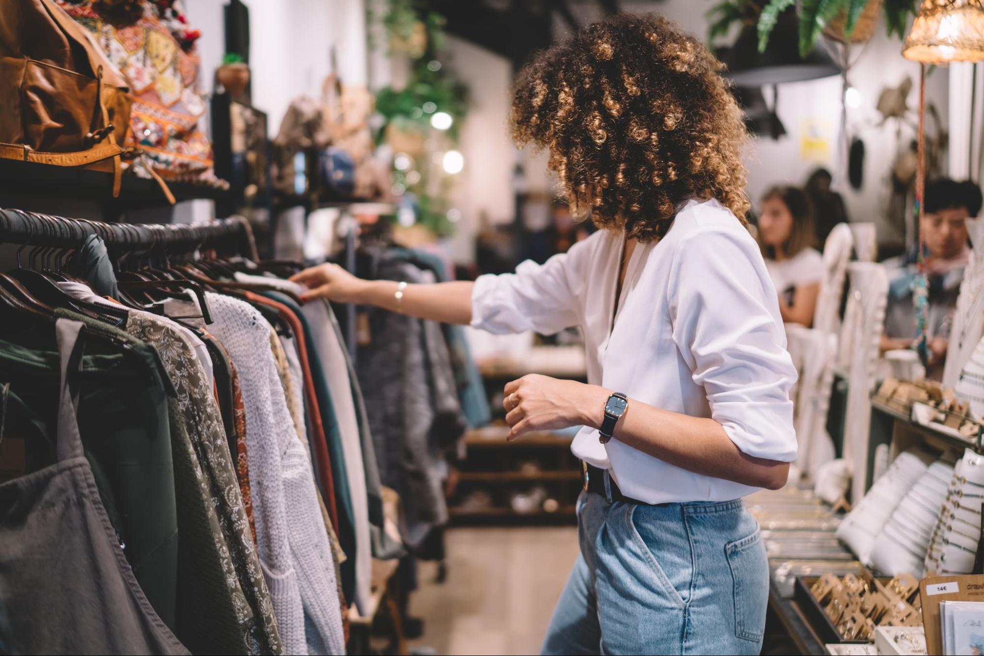 A visual merchandiser inspects dresses on a hanger in a store.