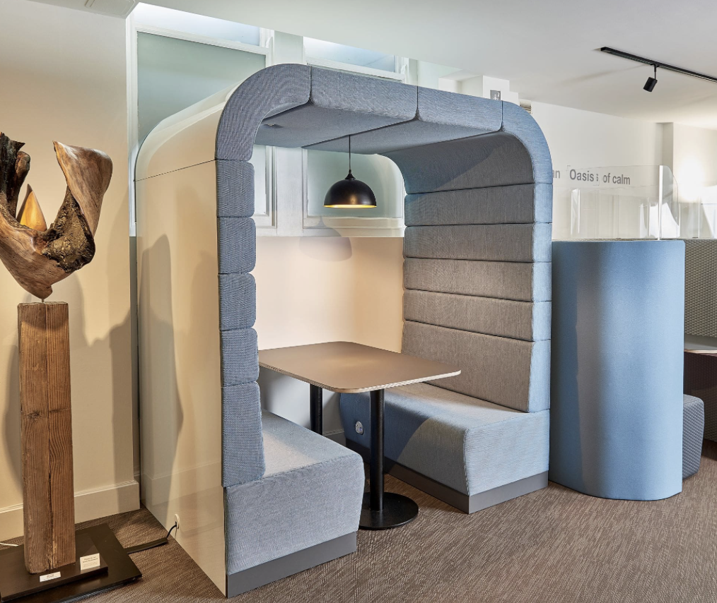 Enclosed office furniture booth with padded seating and a small table. Enclosed office furniture booth with padded seating and a small table.