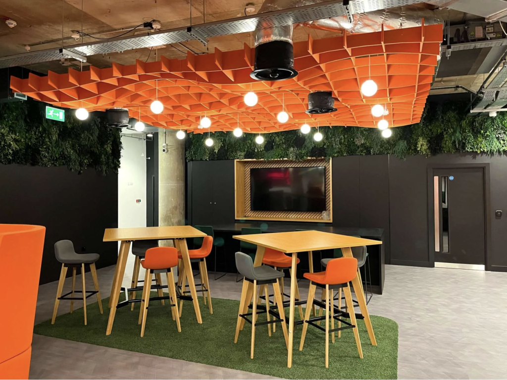 Picture of a creative office furniture design with orange acoustic ceiling panels, high tables, and stools.
Picture of a creative office furniture design with orange acoustic ceiling panels, high tables, and stools.