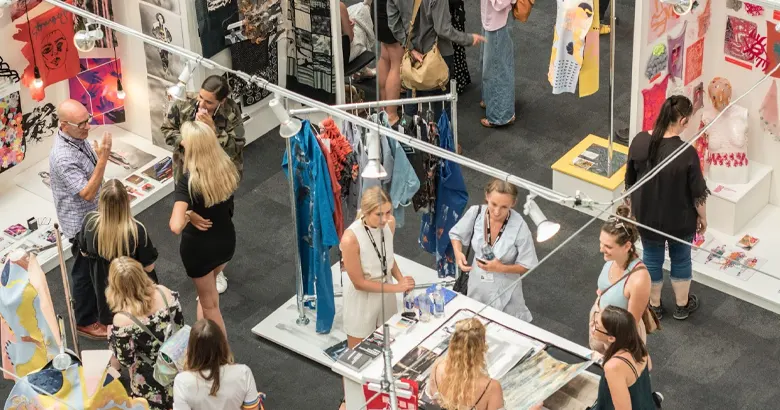 Picture of a trade show with a crowd exploring clothing displays.