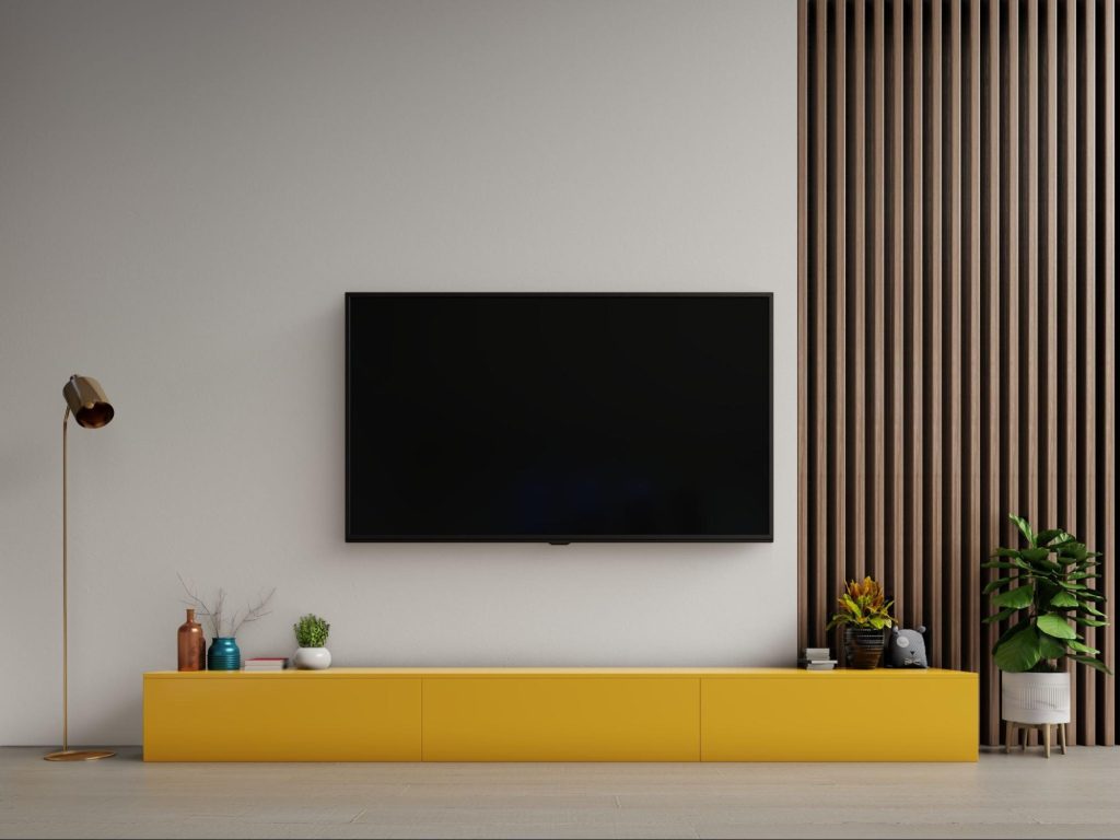 A modern living room with a wall-mounted TV above a bright yellow cabinet.
A modern living room with a wall-mounted TV above a bright yellow cabinet.