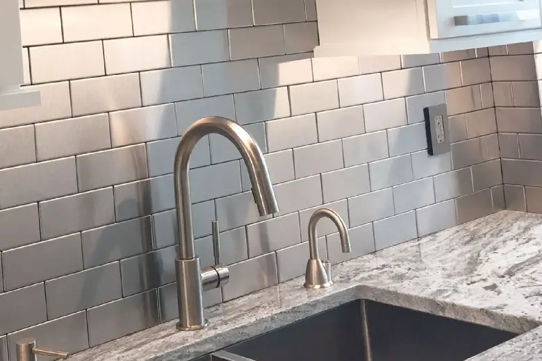 Picture of a kitchen with a stainless steel subway tile backsplash.
