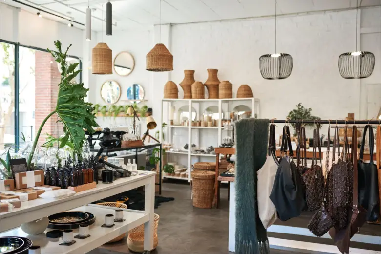 A nature-inspired shop interior design with woven baskets, hanging planters, and white shelving.