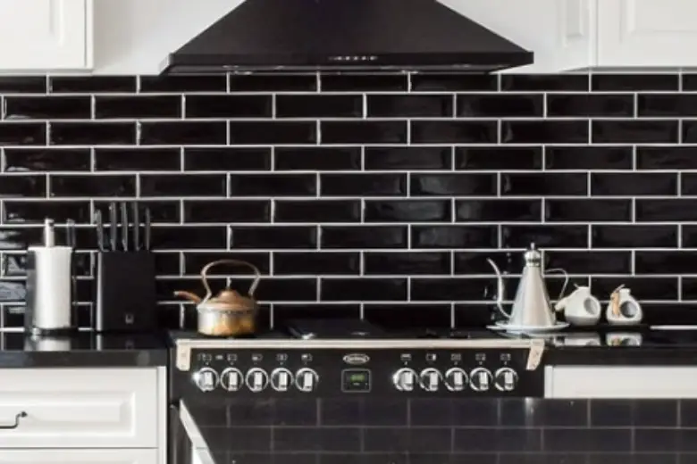 A kitchen with a black subway tile backsplash.

