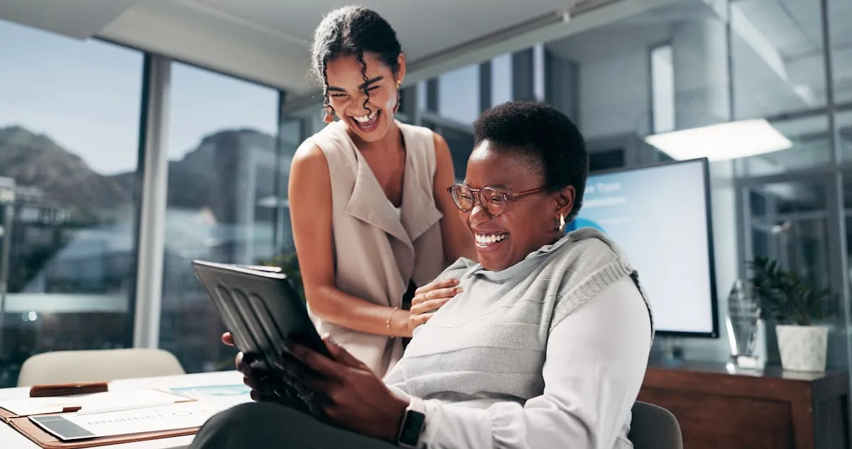 Marketing team laughing together in an office while designing a meme.